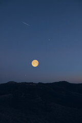 Full Moon, stars, planets, meteor trail and landscape scenery silhouettes.