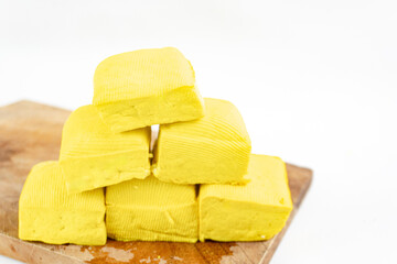 yellow raw tofu on cutting board isolated on a white background. Tofu is a food made from soybeans that has a variety of uses in cooking.