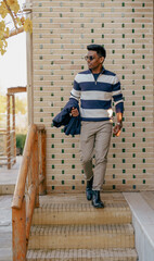 A man wearing a striped sweater and khaki pants walks up a set of stairs