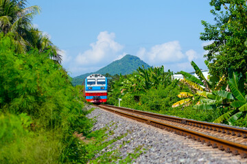 Freight train wagons container locomotive travels along the railway sunny day tropical jungle country hill landscape