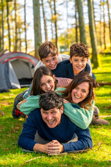 Fototapeta premium Cheerful family laughing while lying down together at forest
