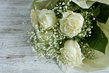 Bouquet of white roses and gypsophila on a wooden background