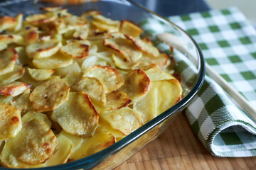 Potato gratin in a glass baking dish on a wooden background