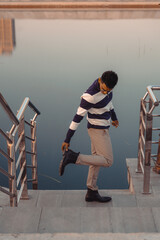 A man in a striped shirt is walking down a set of stairs