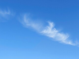 A tranquil blue sky with a few wispy stratus clouds stretching across the horizon, calming, gentle, muted