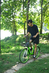 Obraz premium Young attractive man riding a bike through the forest road