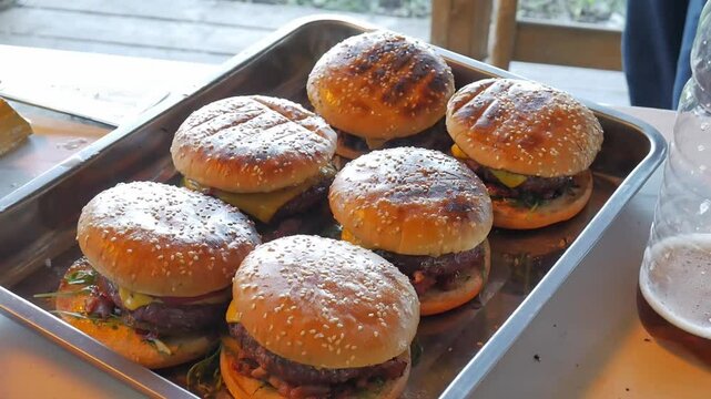 Making burgers and hamburgers outdoor.  Cook preparing cheesebugres. Male checks readinessof cooked cheeseburger