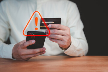 A person holding a credit card and smartphone with a red warning sign overlay, symbolizing online scams, fraud, security risks, and financial caution in digital transactions.