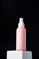 Cosmetic pink bottle. Womens cosmetic accessory for makeup with stylish props on black background.