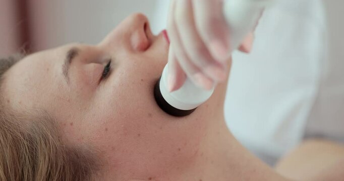 Facial lifting, wrinkle smoothing and rhytide effacement procedure. Beautician moves manipulator on female face. Cosmetology and SPA concept.