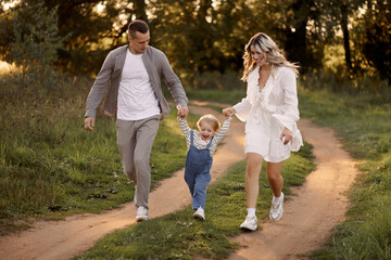 Happy family walking on the grass in the summer park. Mother father and children playing in nature. Children Protection Day. 