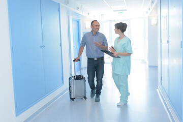 man with suitcase being admitted to hospital by nurse