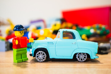 Fototapeta premium Lego toy of a man with a hat standing next to his classic car