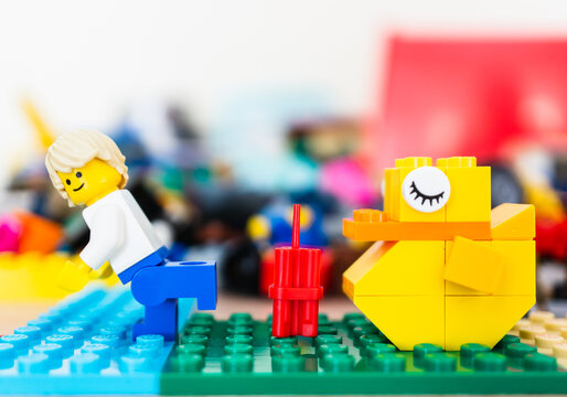 Lego toy of a Man running away from dynamite placed in front of a sleeping yellow duck