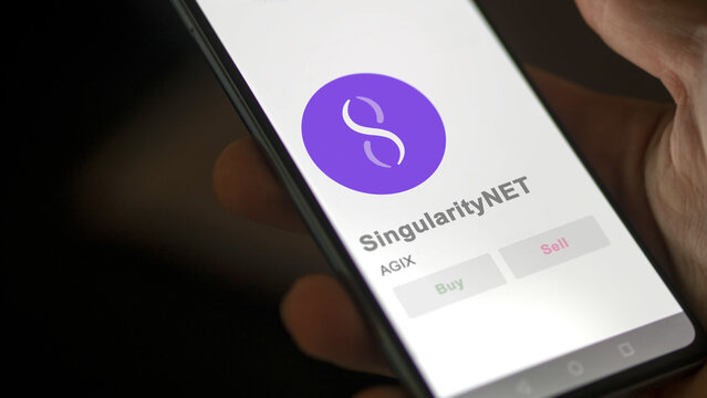 Close up on logo of AGIX SingularityNET on the screen of an exchange. AGIX SingularityNET price stocks, $AGIX on a device.