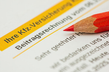 Auf der Beitragsrechnung für Kfz-Versicherung liegt ein Rotstift