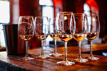 Sunlit Whispers: A Tableau of White Wine Glasses, Glimmering with Reflections on Rustic Wood.