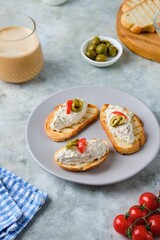 Cold appetizer, mackerel rillettes on white bread toasts on ceramic plate on gray concrete background. Recipes fish, seafood.