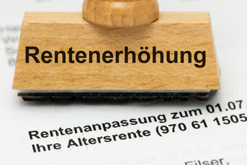 Ein Holzstempel mit Aufdruck Rentenerhöhung steht auf einem Rentenbescheid - Symbolbild
