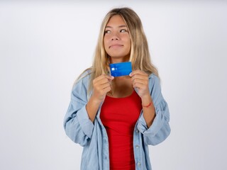 Photo of cheerful Beautiful teen girl wearing denim jacket hold debit card look empty space