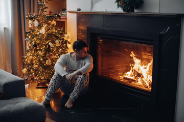 a man is sitting by the fireplace and looking at the fire