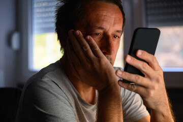 Bored dull mature adult man looking at his mobile phone