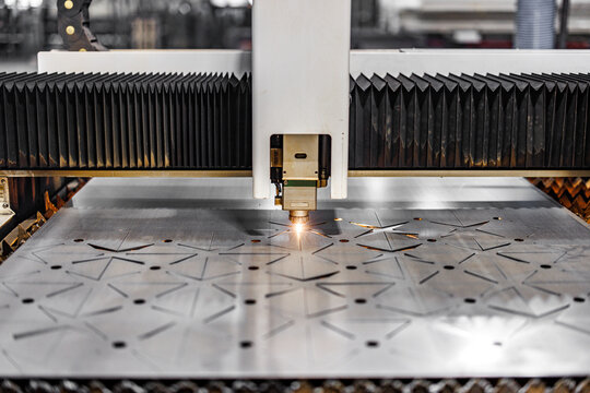 Precision in Motion: A laser cutting machine seamlessly etches intricate patterns onto a gleaming metal sheet, illuminating innovation in the heart of modern engineering.
