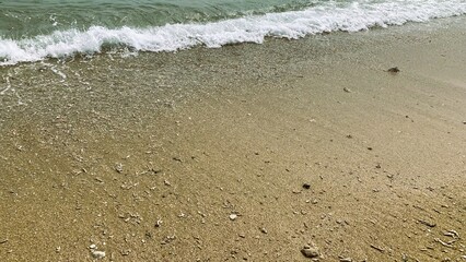 Small waves on a beach, Tiny waves lapped at the shore. Gentle ripples danced across the calm, shallow water. Kondang Merak Beach in Malang Indonesia