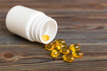 Soft gels pills with Omega-3 oil spilling out of pill bottle close-up. Gel capsules bottle white...