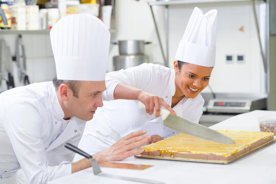 master chef guiding trainee cutting large dessert