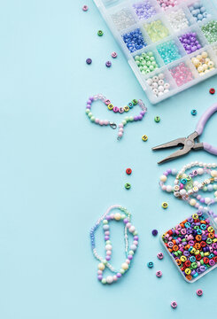 Colorful beads and pliers creating friendship bracelets on blue background