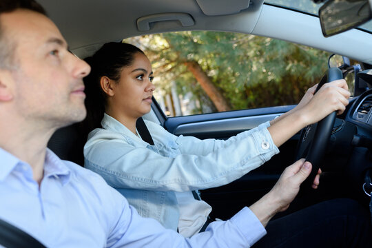 driving school instructor guiding steering wheel for female learner
