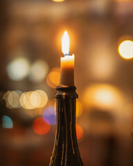 Burning candle on the brown bottle on bokeh background.