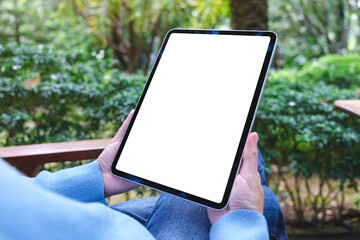 Mockup image of a woman holding digital tablet with blank white desktop screen in the outdoors