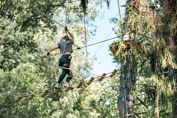 A woman skillfully navigating a challenging tree climbing course while surrounded by vibrant and...