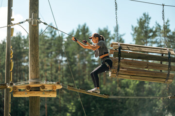 A woman navigates a thrilling rope course, showcasing balance and agility in an outdoor adventure...