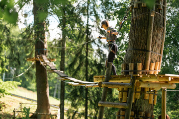 A young woman skillfully navigates a challenging treetop obstacle course in a vibrant, lush green forest