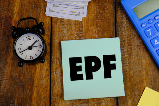 EPF or employee provident fund concept with money, calculator and black alarm, clock. Business and economy concept on wooden table 