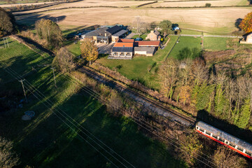 Aerial photo of the beautiful British town of Bedale a market town in the Hambleton former district of North Yorkshire in the UK showing a farm house along side train tracks in the Autumn time