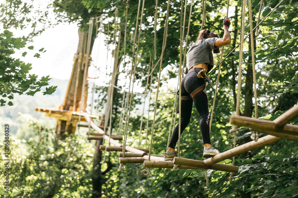 Wall mural a woman skillfully navigating a challenging tree climbing course while surrounded by vibrant and lus