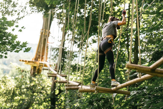 A woman skillfully navigating a challenging tree climbing course while surrounded by vibrant and lush greenery