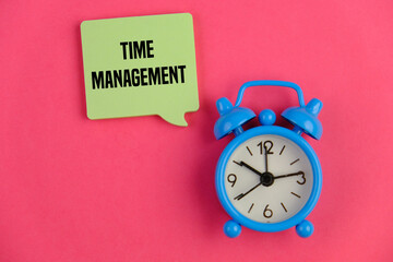 text of TIME MANAGEMENT on yellow note pad over pink background with blue alarm clock beside