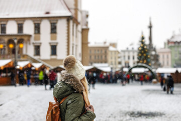 Woman tourist is going to Christmas market at town square during Advent holiday. Lifestyle in city...