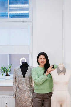 Smiling design professional standing amidst dummies in studio