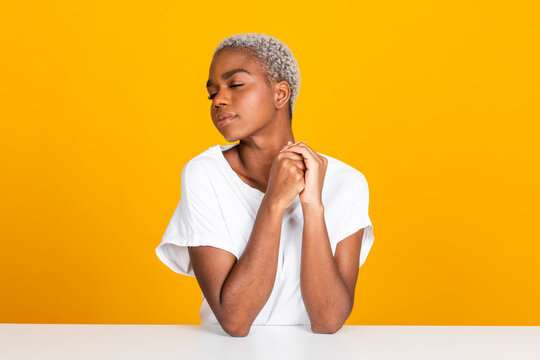 Woman sitting with eyes closed at table against yellow background