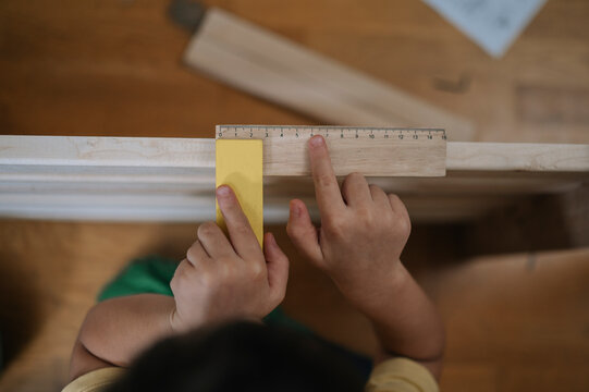 Boy measuring furniture with ruler at home