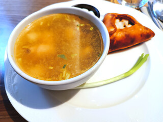 Appetizing tasty pike perch and trout soup with green onions and belyash