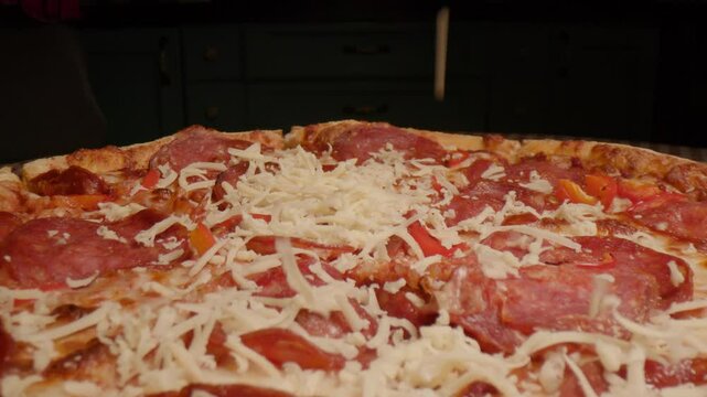 A close-up shot of grated cheese falling onto a pepperoni pizza, melting perfectly on the hot, savory toppings. Capturing a delicious moment of pizza preparation