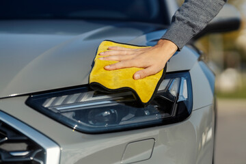 Close up of a man's hand cleaning his car with a cloth at car wash.