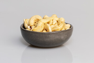 Cashew nuts in grey bowl on white background. 